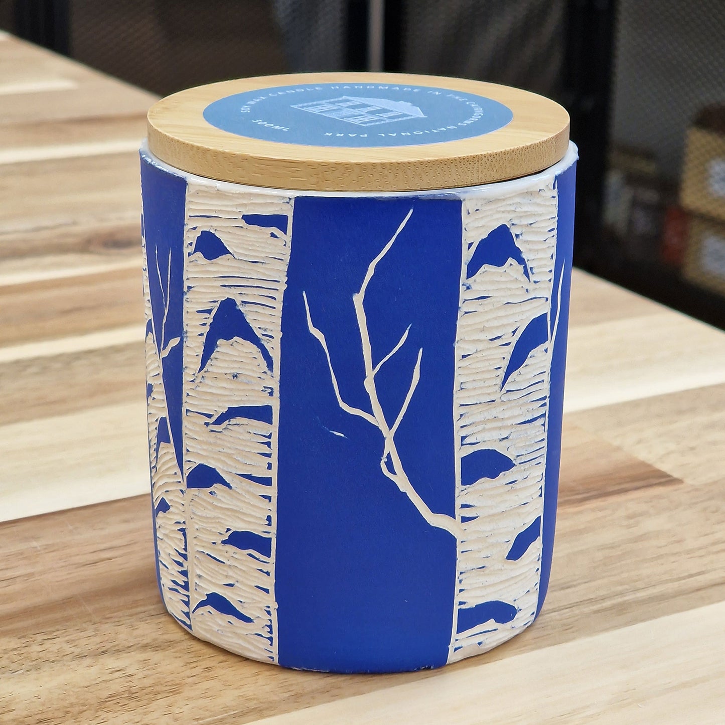 A lidded ceramic pot with a birch tree carving on the surface