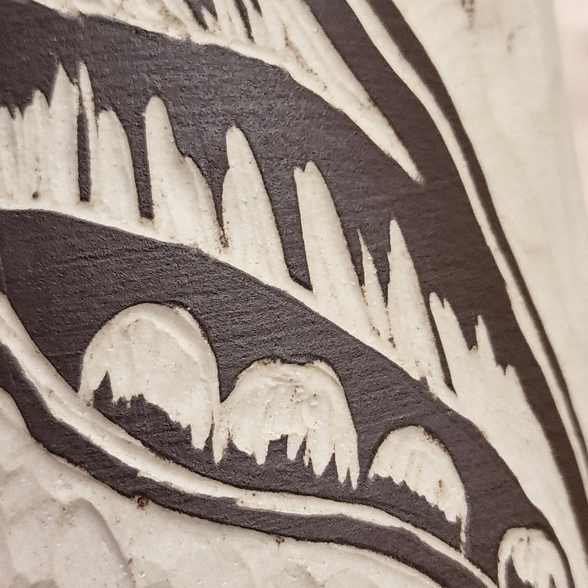 A close-up of a sgraffito product, in which a carving has been made, producing a decorative pattern on the ceramic surface